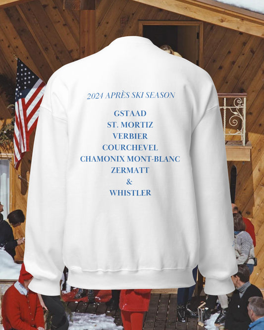 White Après Ski crew sweatshirt worn at a ski chalet, back view listing the season's resorts