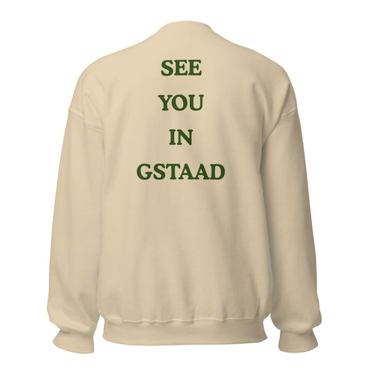 Green graphic text reading See You in Gstaad on the back of a sand crewneck sweatshirt