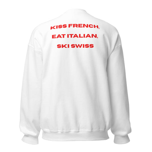 Red graphic text reading Kiss French, Eat Italian, Ski Swiss on the back of a white crewneck sweatshirt